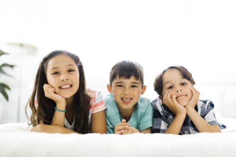 Siblings (10-11, 6-7, 8-9) lying in bed side by side