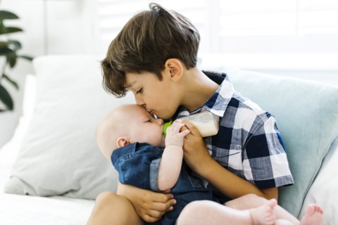 Boy( 6-7) feeding small brother (12-17 months)