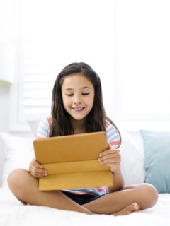 Smiling girl  (10-11) sitting and watching tablet