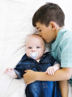 Portrait of boy (8-9) kissing his younger brother (12- 17 months)