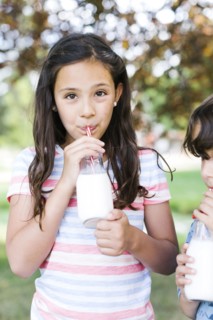 Girl (10-11) and boy (6-7)   in park drinking milk