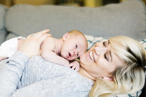 Mother lying on sofa and holding  his one day son (0-1 months)