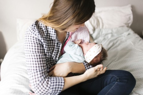 Young mother with baby girl (0-1 months) sitting in bedroom