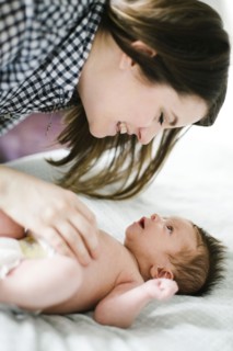 Young mother with baby girl (0-1 months) lying on bed