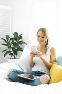 Young woman with mobile phone sitting on sofa