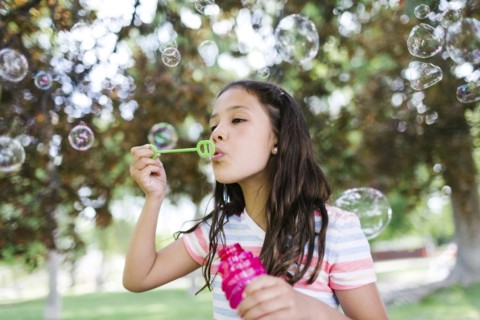 Portrait of girl ( 10-11 )  blowing soap bubbles