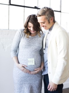 Portrait of men and smiling pregnant woman with adhesive note on belly