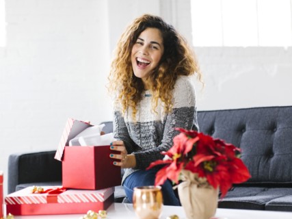 Happy woman on sofa opening Christmas gift