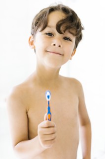 Boy (6-7) holding toothbrush