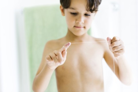 Boy (6-7) flossing teeth