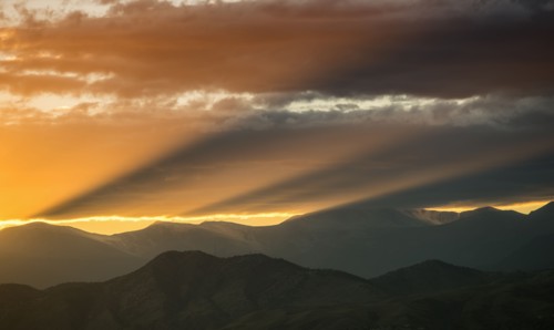 USA, Colorado, Denver, Setting sun shining through clouds over Front Range