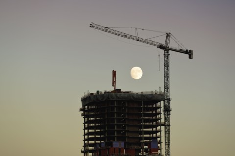 USA, Colorado, Denver, Full moon in background of skyscraper construction site at dusk