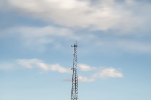 Top of communications tower with sky and clouds in background