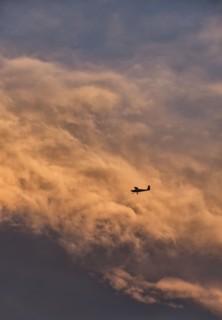 Small plane in sky with clouds in background