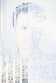 Double exposure portrait of mature man on office building facade