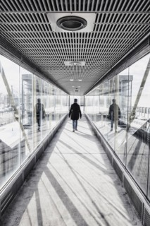 USA, Massachusetts, Boston, Woman walking down glass and metallic walkway at train station