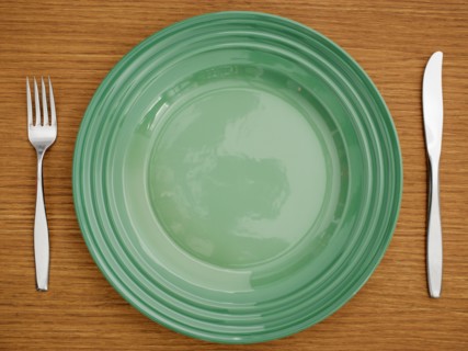 Studio shot of green plate with fork and knife