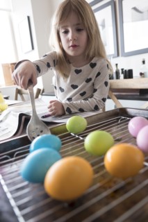 Girl (4-5) making colored Easter eggs