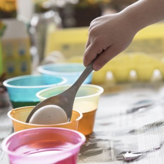 Girl (4-5) making colored Easter eggs