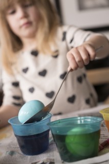 Girl (4-5) making colored Easter eggs