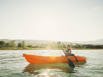 Girl (4-5) kayaking on lake at sunset