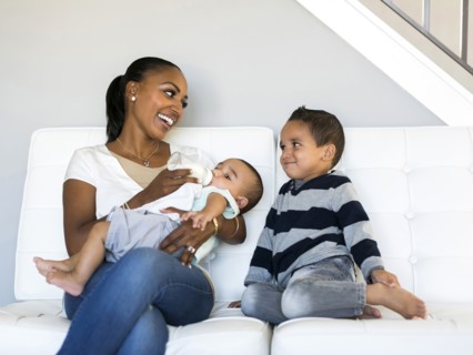 Mother with two sons (2-5 months, 2-3) on sofa