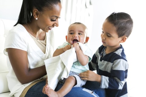 Mother with two sons (2-5 months, 2-3) on sofa