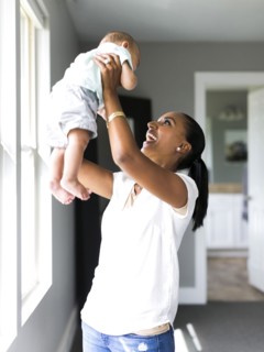 Mother holding aloft baby boy (2-5 months)