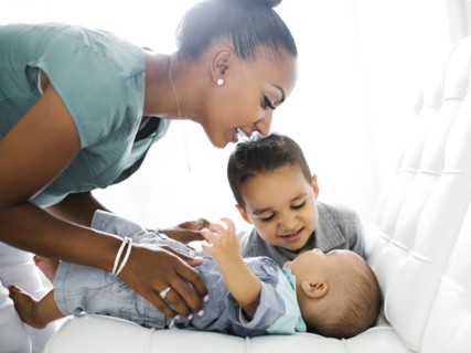 Mother with two sons (2-5 months, 2-3) on sofa