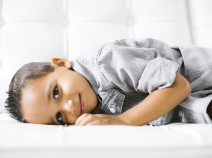 Boy (2-3) lying down on white sofa