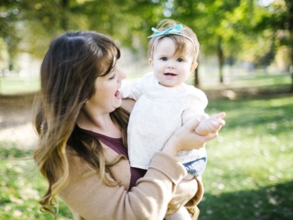 Portrait of mother carrying daughter (12-17 months) in park
