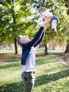 Father throwing daughter (12-17 months) up in air in park