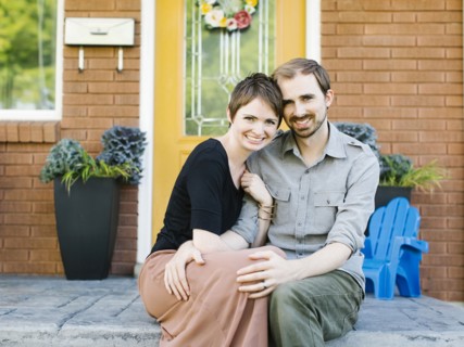 Happy couple sitting in front of house