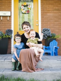 Mother with daughters (2-3, 12-17 months) sitting in front of house