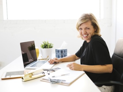 Woman using laptop, looking at camera