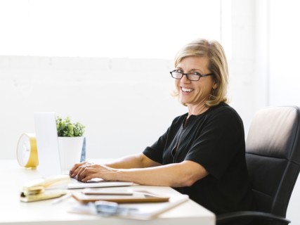 Portrait of Mature woman in office typing on laptop