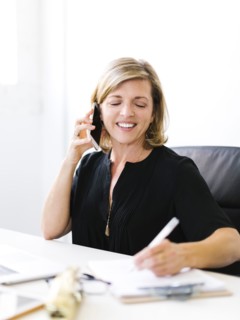 Mature woman talking on mobile phone and taking notes