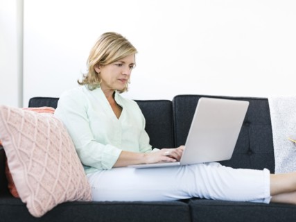 Woman sitting on sofa and using laptop