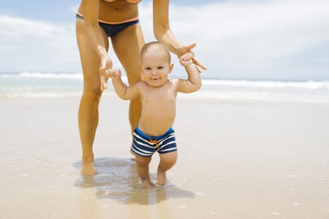Son (12-17 months) learning to walk with mother on beach