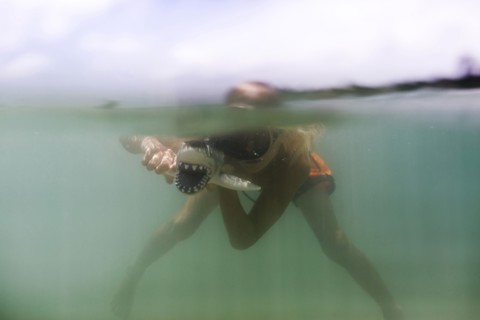 Boy (8-9) playing with toy shark in sea