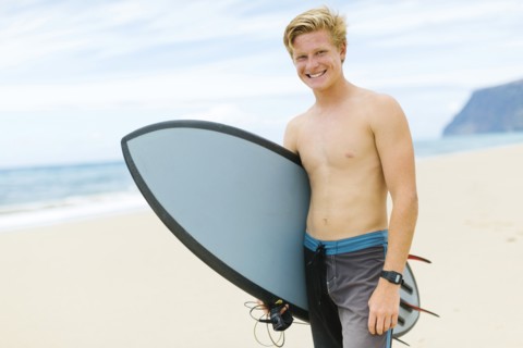 Man standing on beach and holding surfboard
