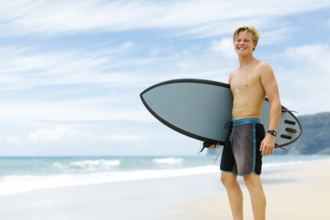 Man standing on beach and holding surfboard