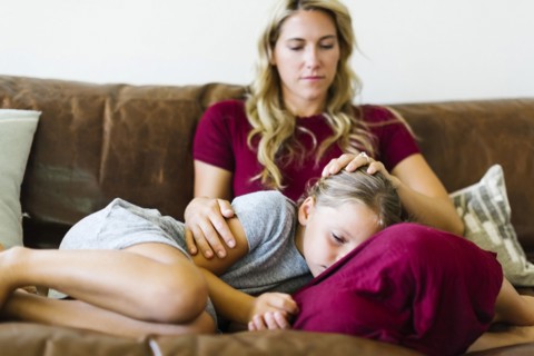 Woman sitting with daughter (6-7) on couch