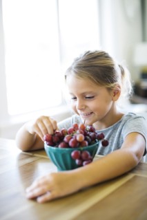 Young girl (6-7) eating fresh grapes