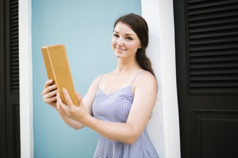 Woman with tablet doing selfie on city street
