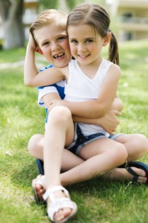 Sister and brother (4-5, 6-7) embracing in park