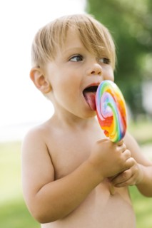 Boy (2-3) licking lollipop