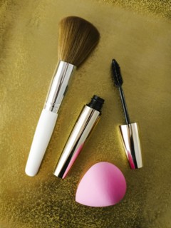 Mascara, make-up brush and small sponge on shiny background