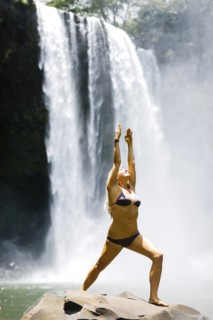 USA, Hawaii, Kauai, Woman practicing yoga next to waterfall