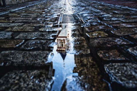 Spain, Andalusia, Seville, La Macarena, Church reflecting on wet cobblestone street
